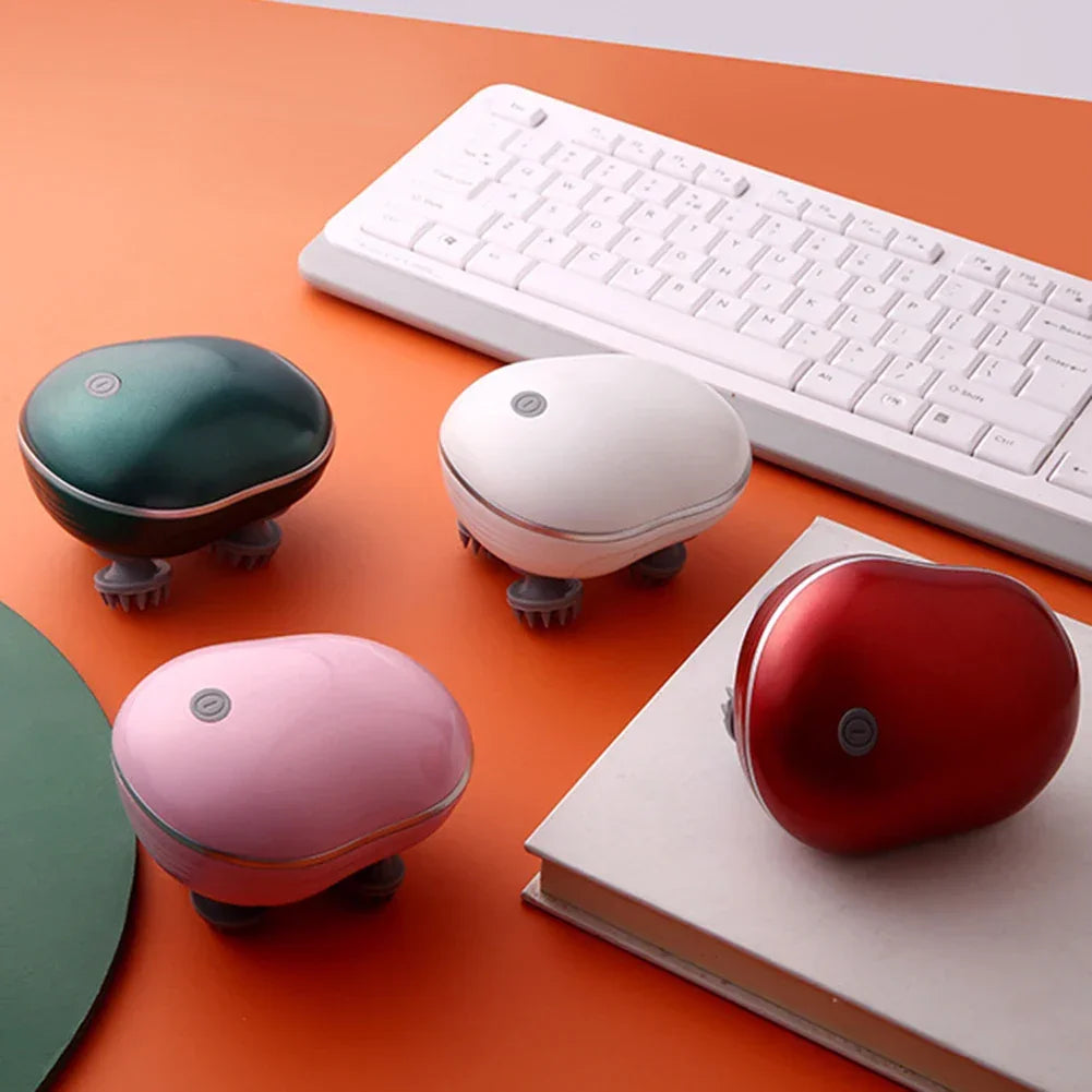 Portable handheld scalp massagers in green, white, pink, and red on an orange desk with a white keyboard and book